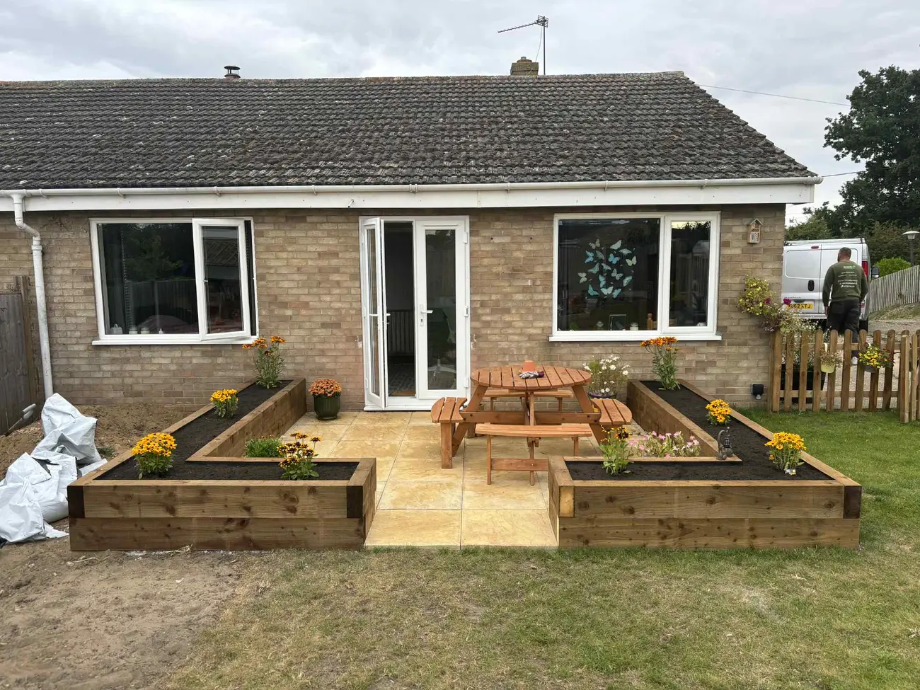 Newly laid sandstone patio with timber raised beds planted with marigolds outside a Norwich bungalow